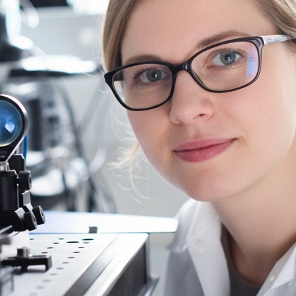 Scientist in a lab looking over an optical setup on an optical bench.
